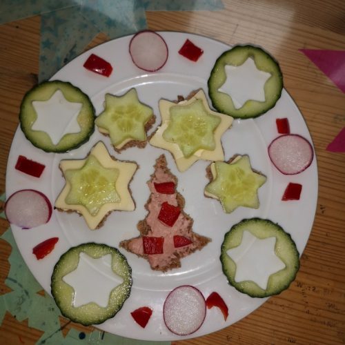 Aus Gurkenscheiben sind Sterne ausgestochen und um einen Tannenbaum aus Brot dekoriert
