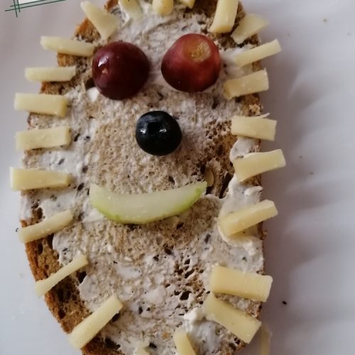 Brot mit Käsestückchen als Stacheln, Obst als Gesicht